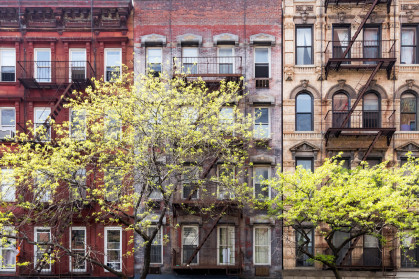 a row of new york city apartments with trees in front.